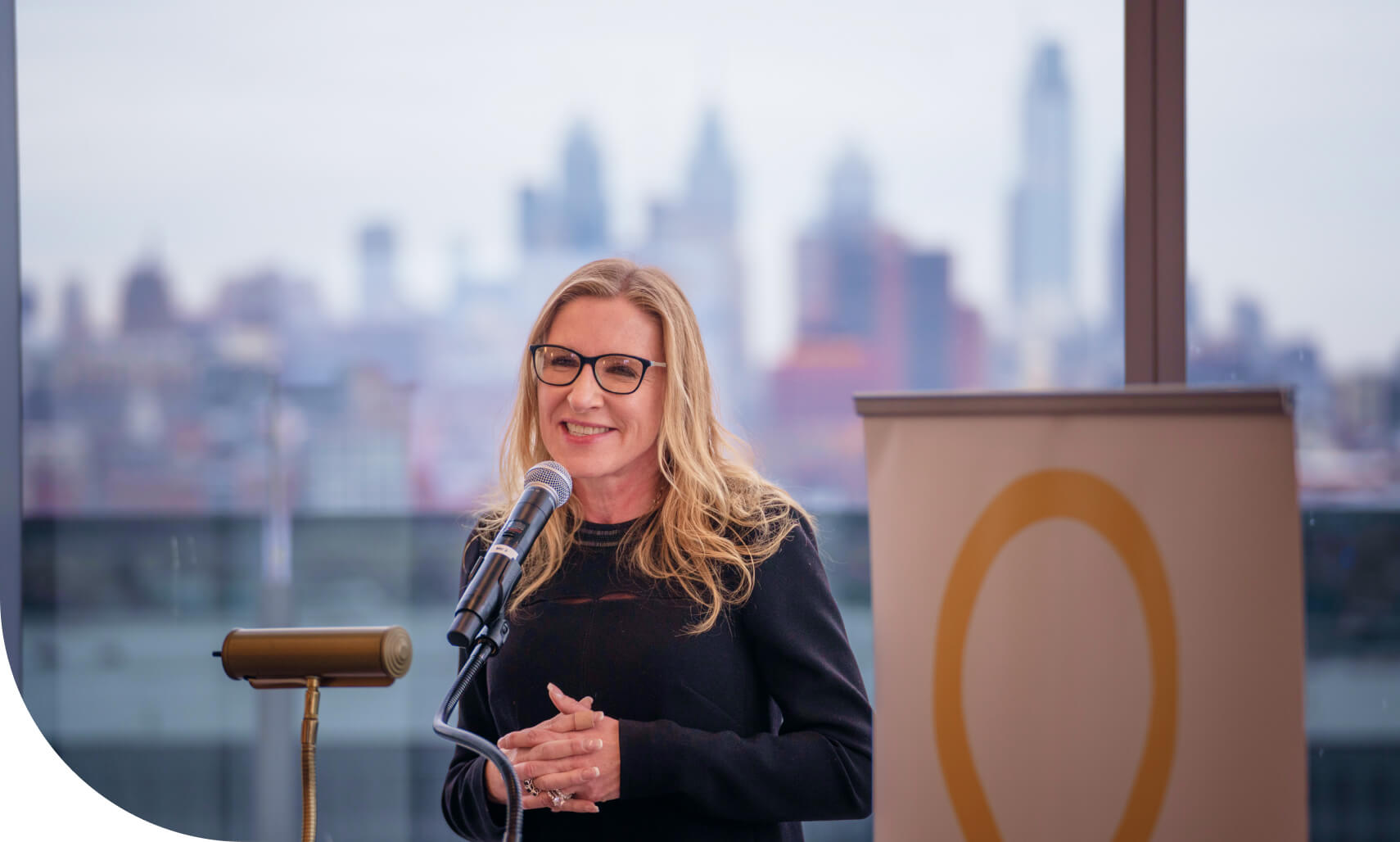 Woman speaking into a microphone on stage at an event.