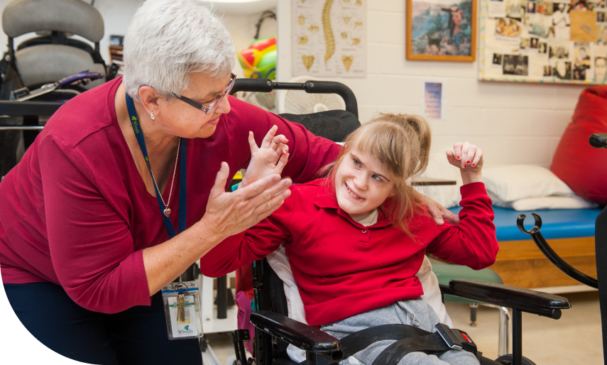 A middle-aged woman and a girl in a wheelchair are looking at each other