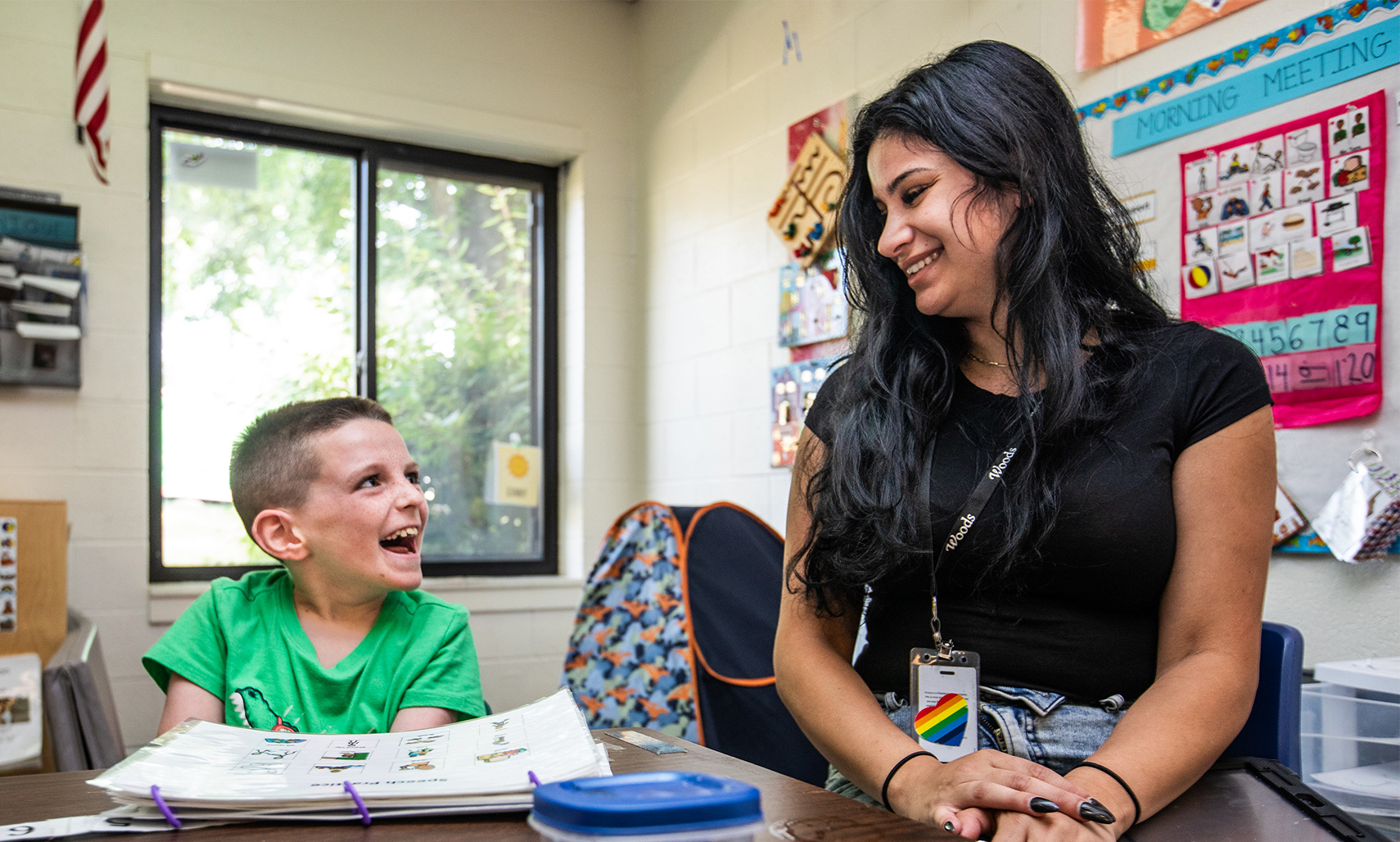 A teacher and a children are smiling at each other