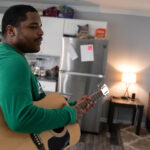 A man is playing a guitar at home