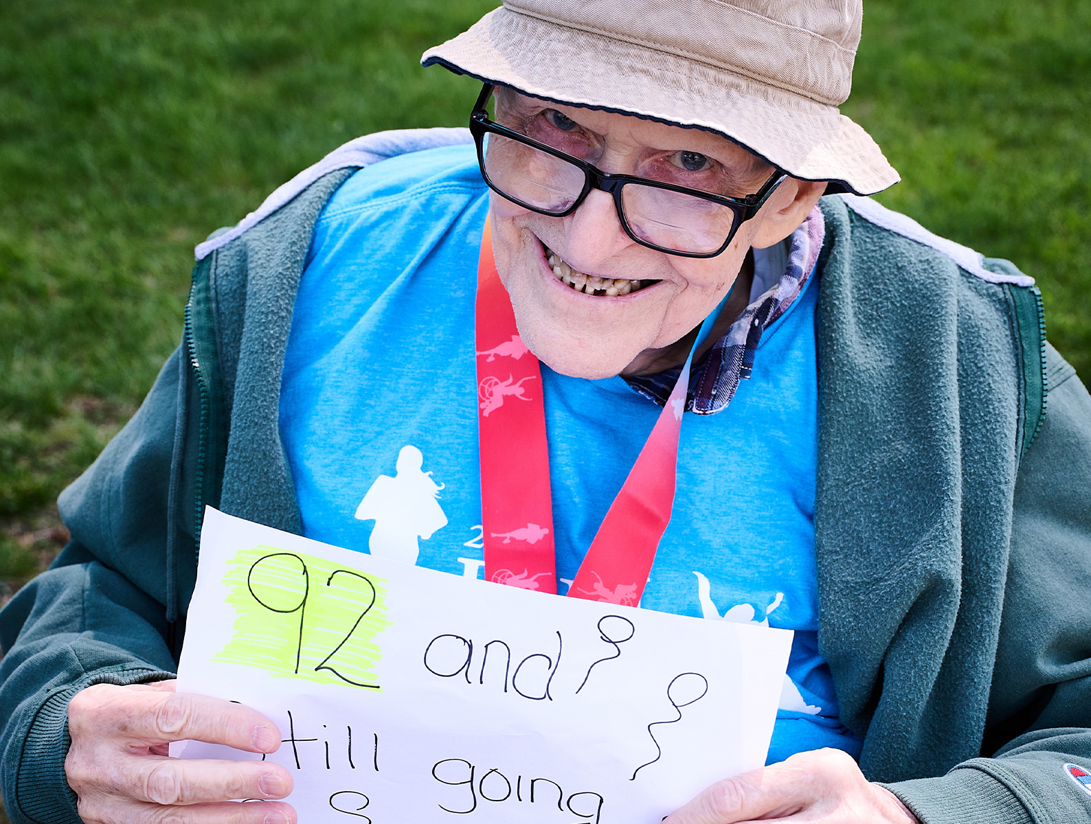 An old man is smiling at the camera while holding a paper