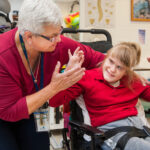 A middle-aged woman and a girl in a wheelchair are looking at each other