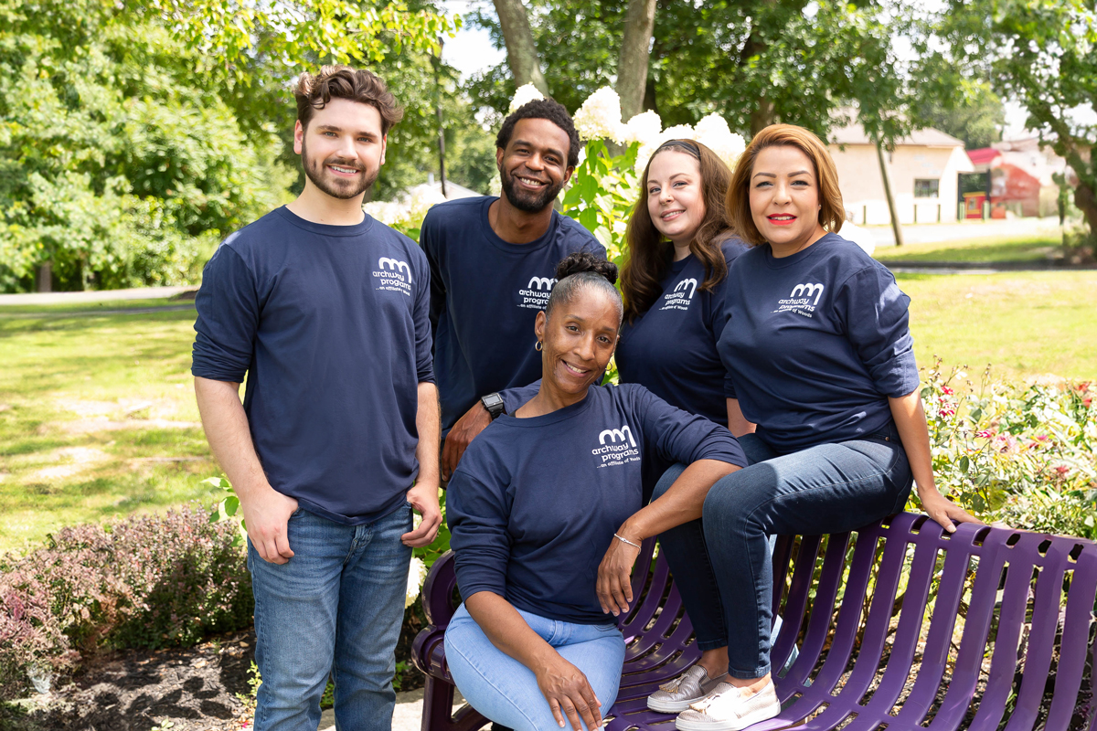 Five people from Archway Programs sitting and standing near a bench