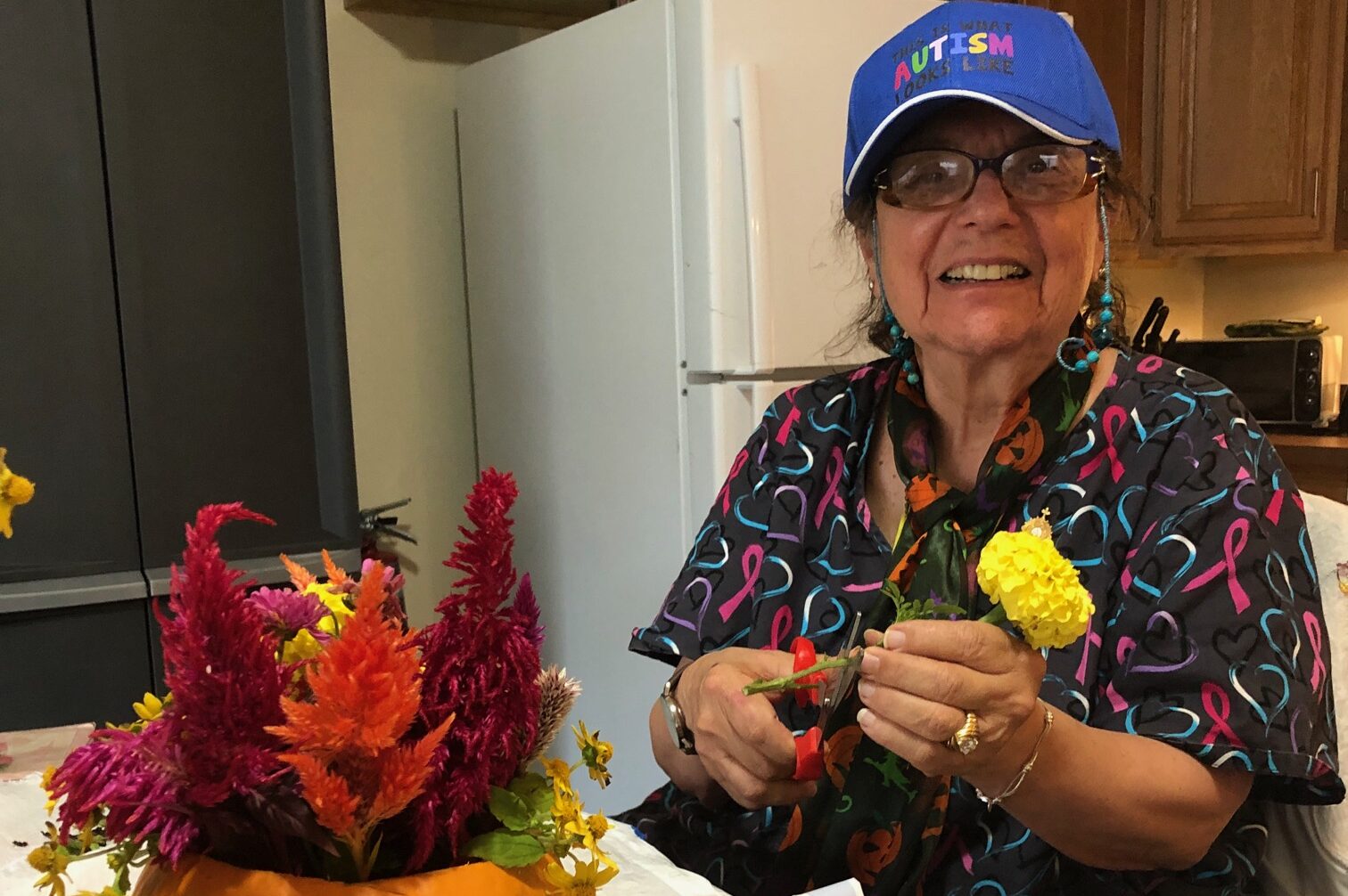 Woman cutting a flower for a fall floral arrangement in a pumpkin