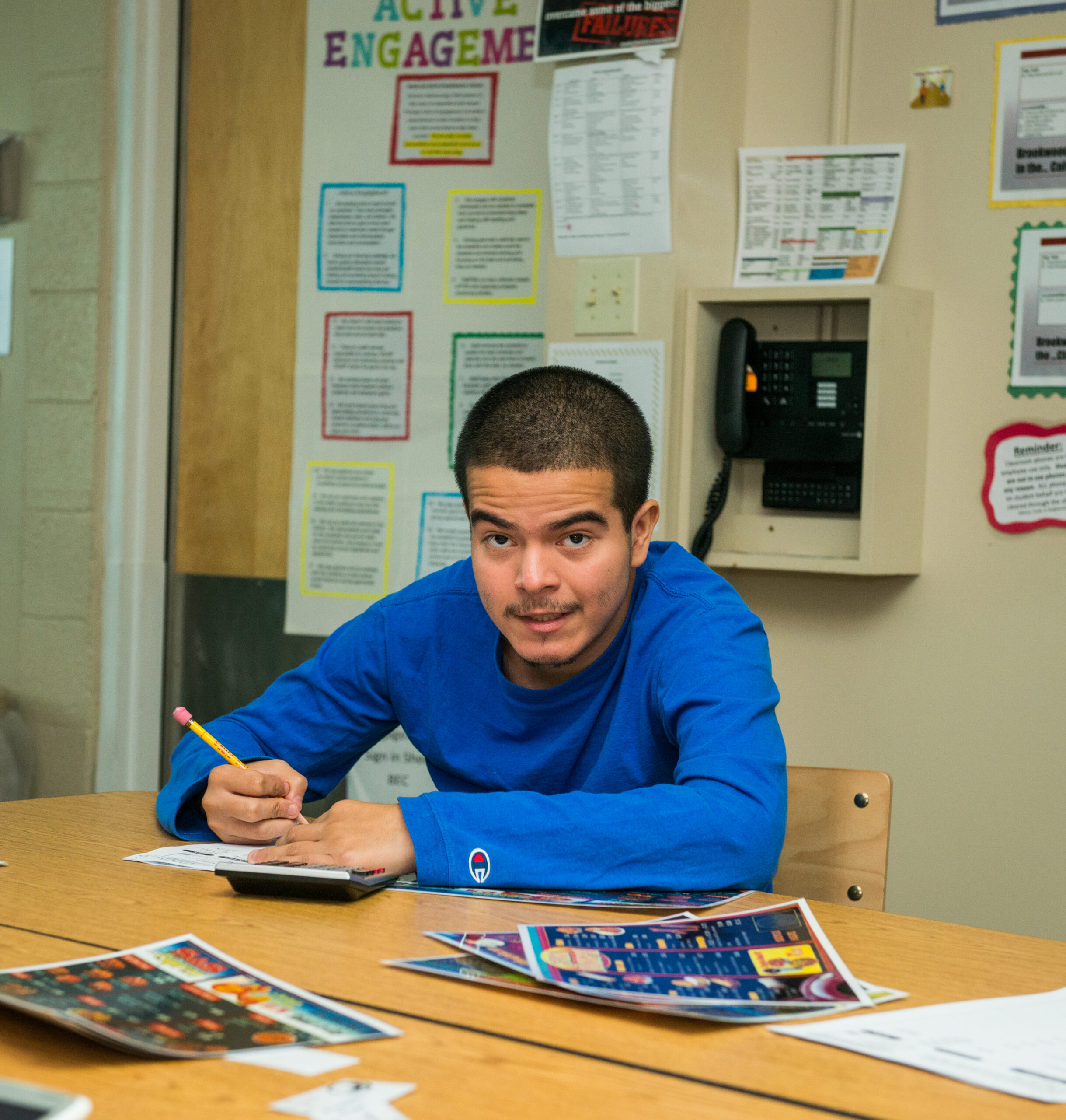 young man with a pencil in his hand writing on a piece of paper and looking up