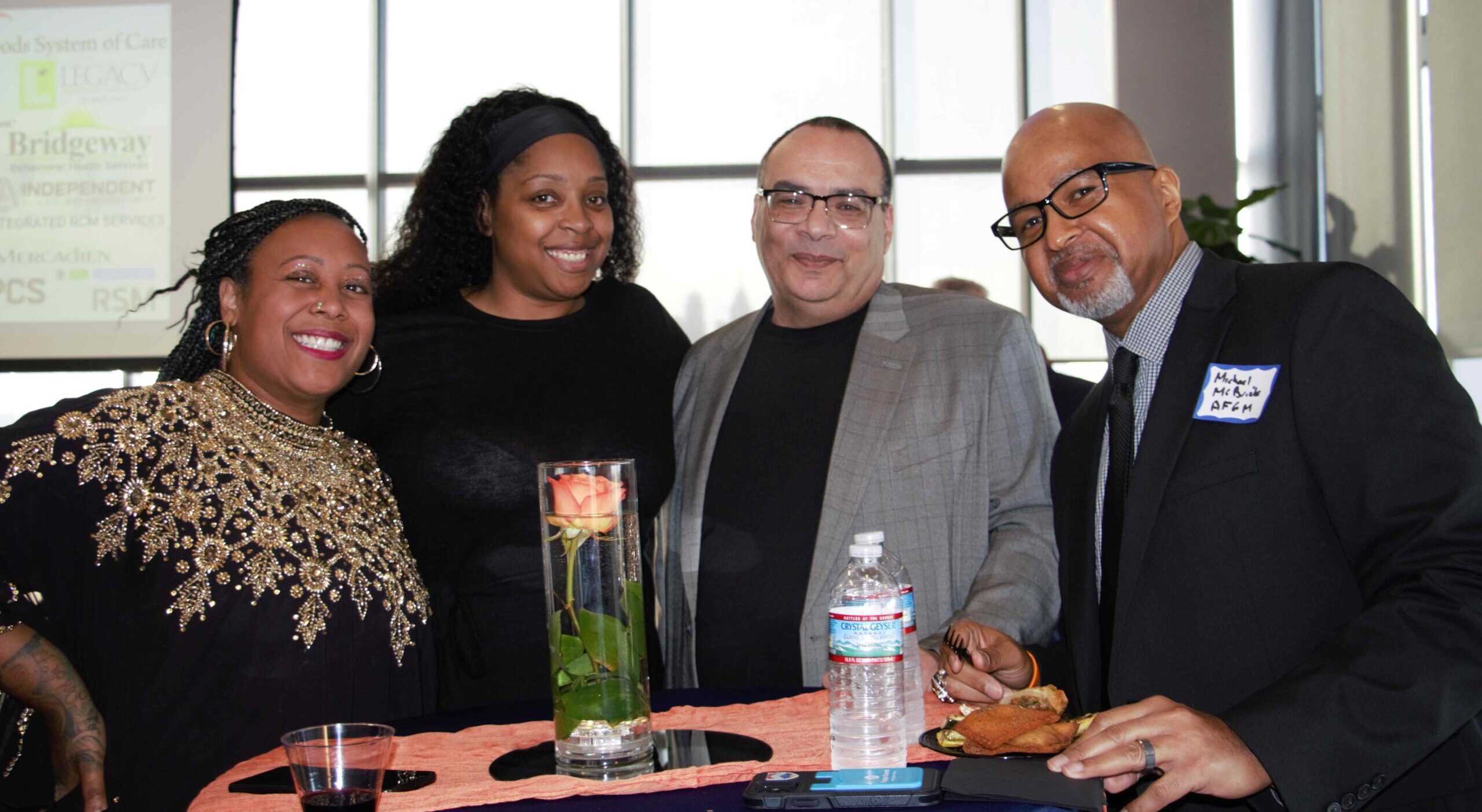 four smiling people around a table