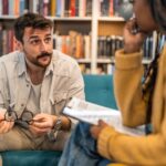 a white man being counseled by a black woman who is sitting across from him