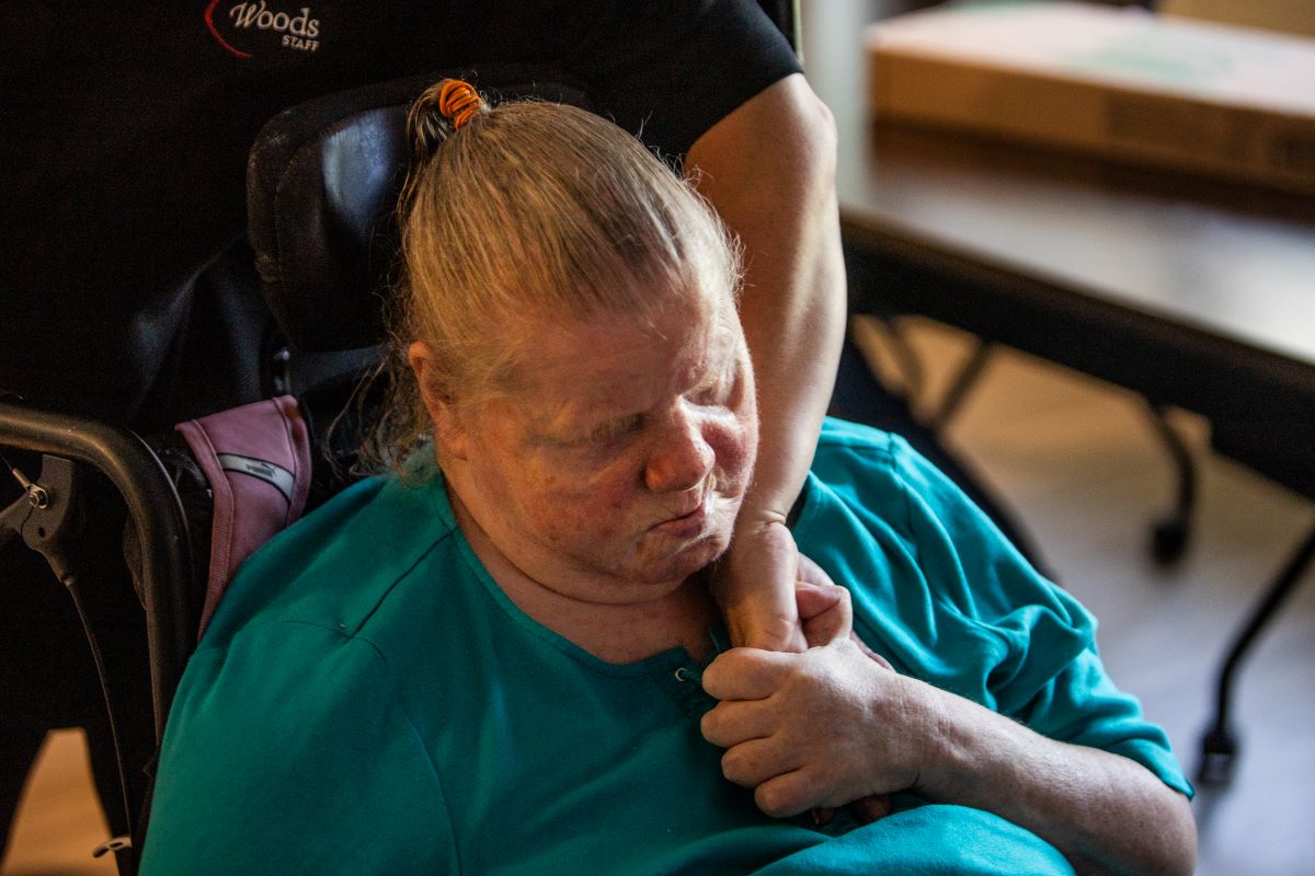 woman in a chair with her eyes closed holding someone's hand