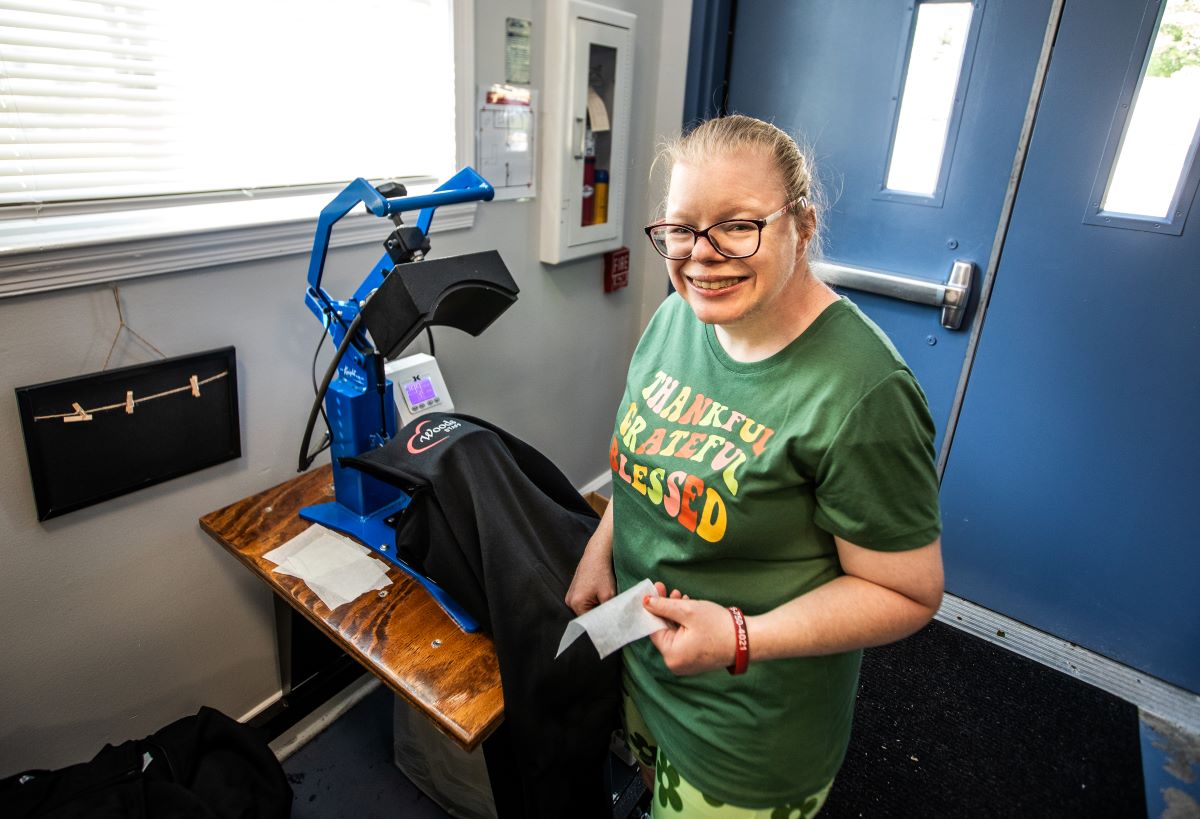 Young woman with an intellectual disability standing beside an embroidery machine