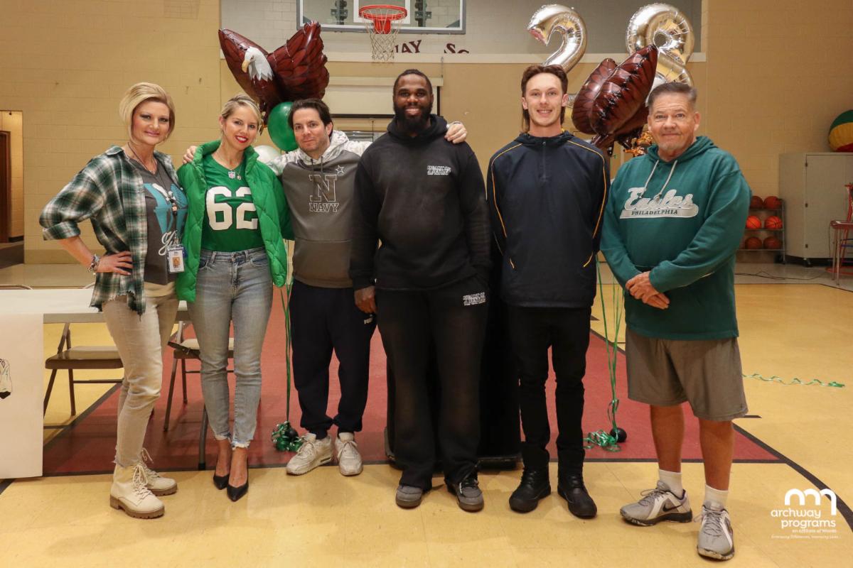 Wendell Smallwood standing with a group of people in a school gymnasium