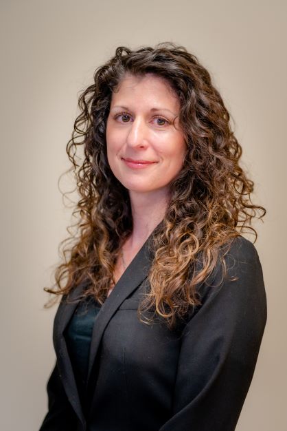 woman with long, curly brown hair wearing a dark blue blazer