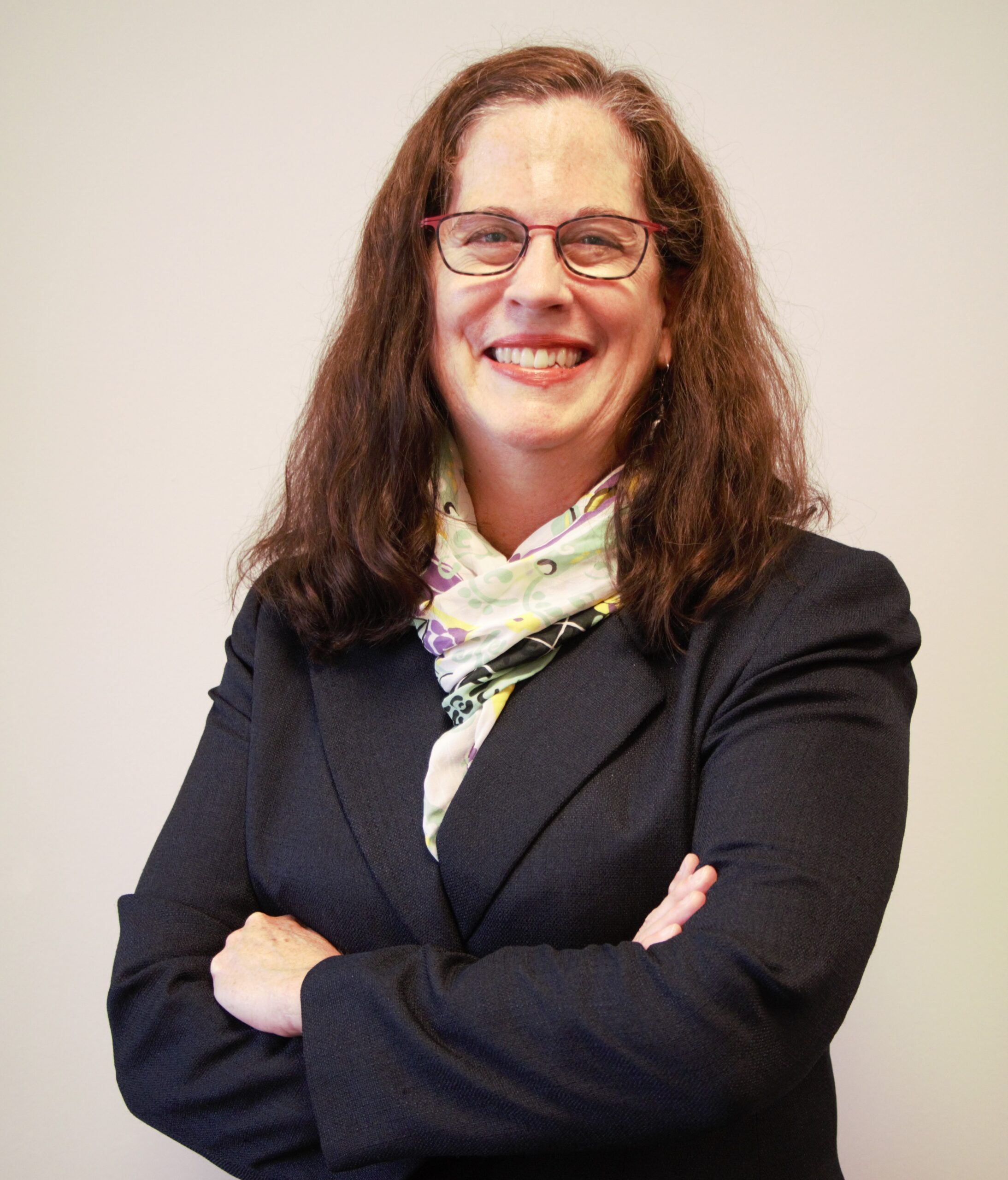 woman with long, curly brown hair wearing a dark blue suit